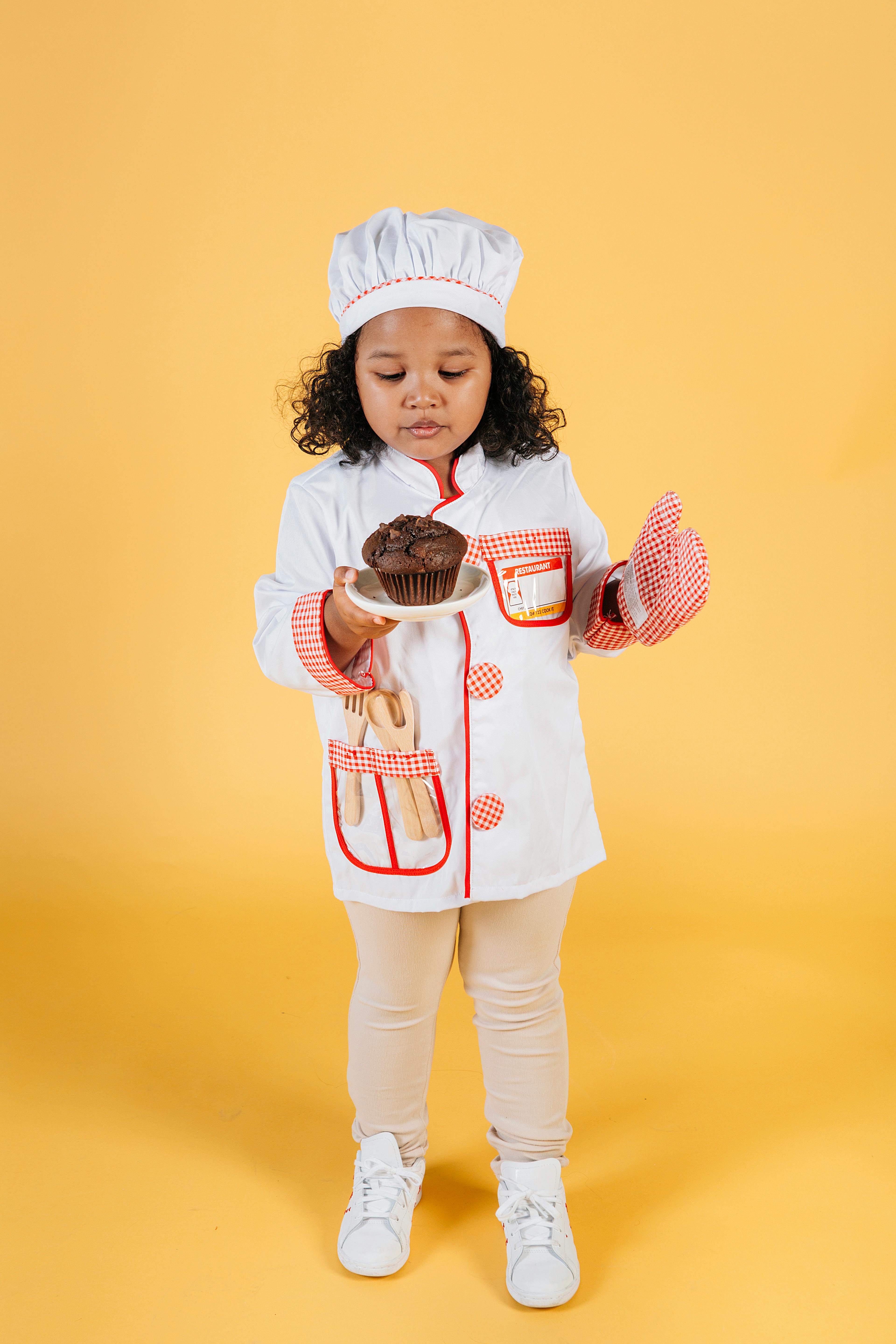 little girl in oven glove blowing on hot chocolate cupcake