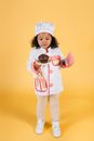 Full body of small African American girl wearing chef uniform standing with plate with yummy chocolate dessert