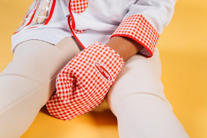 Little child wearing chef uniform with oven glove