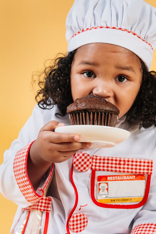 Free Little black girl biting chocolate muffin Stock Photo
