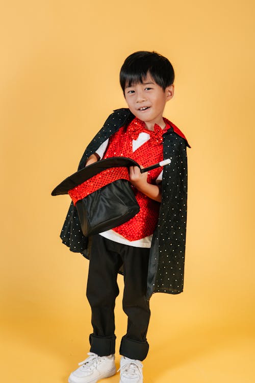 Cute funny Asian boy in costume of magician