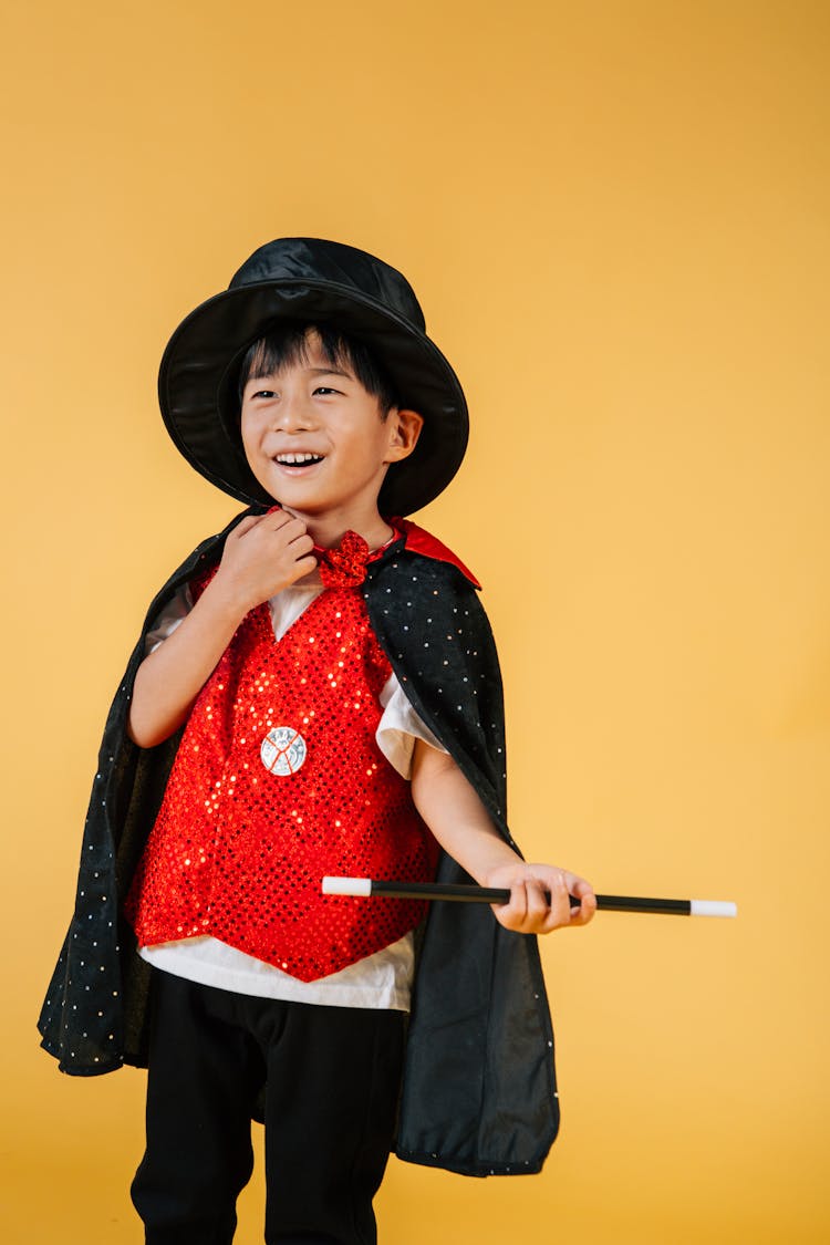 Cheerful Asian Boy With Magic Wand Pretending Magician In Costume