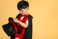 Little ethnic boy in magician costume in studio