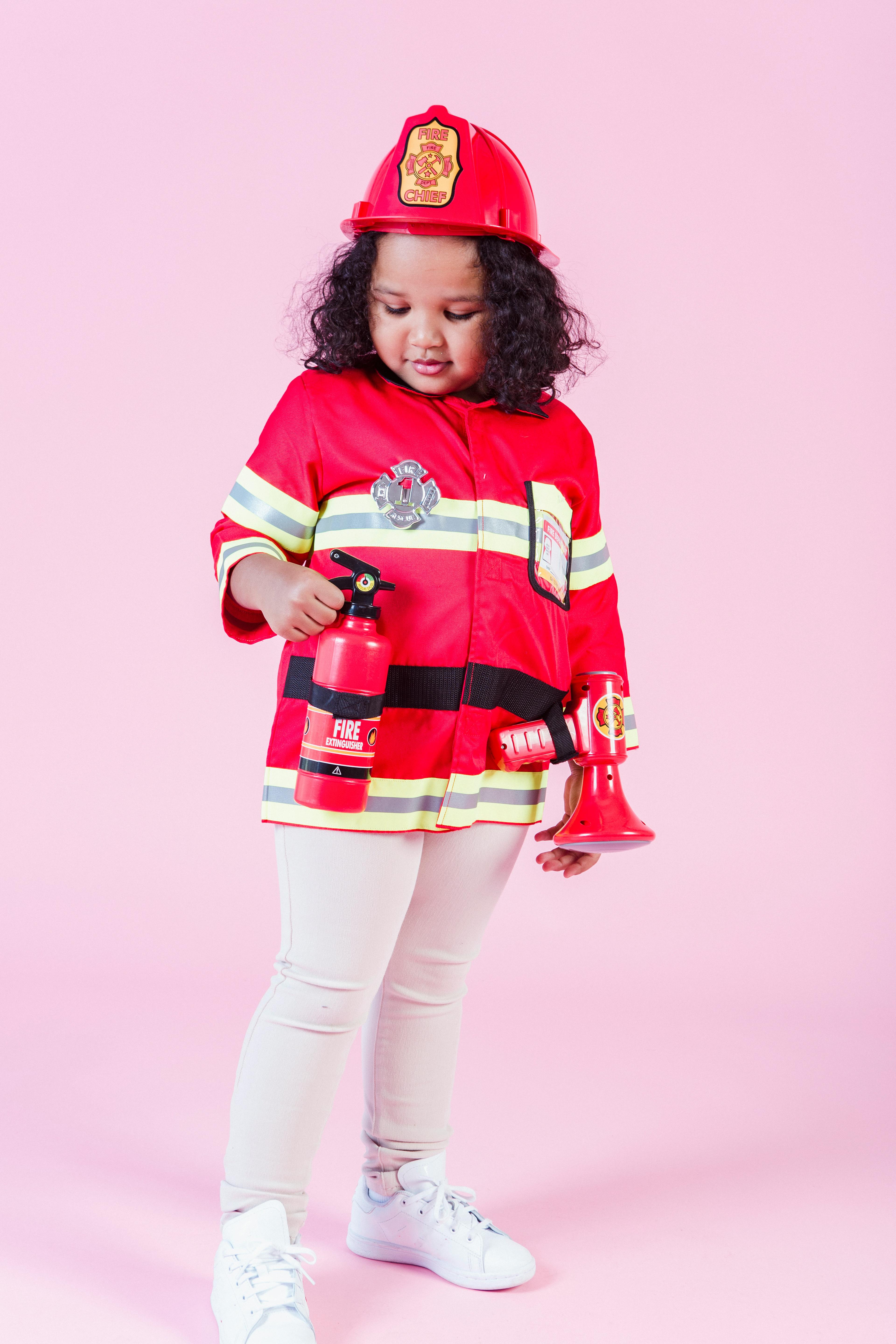 little ethnic girl in fireman costume in studio