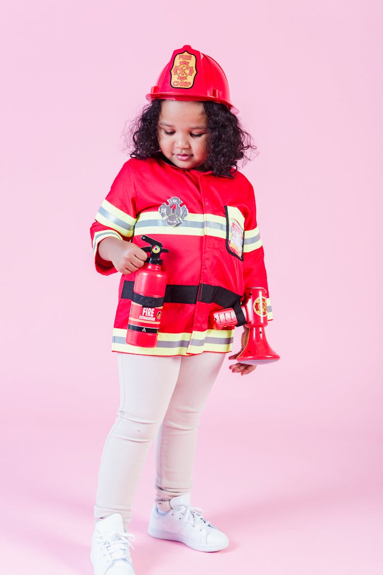 Little Ethnic Girl In Fireman Costume In Studio