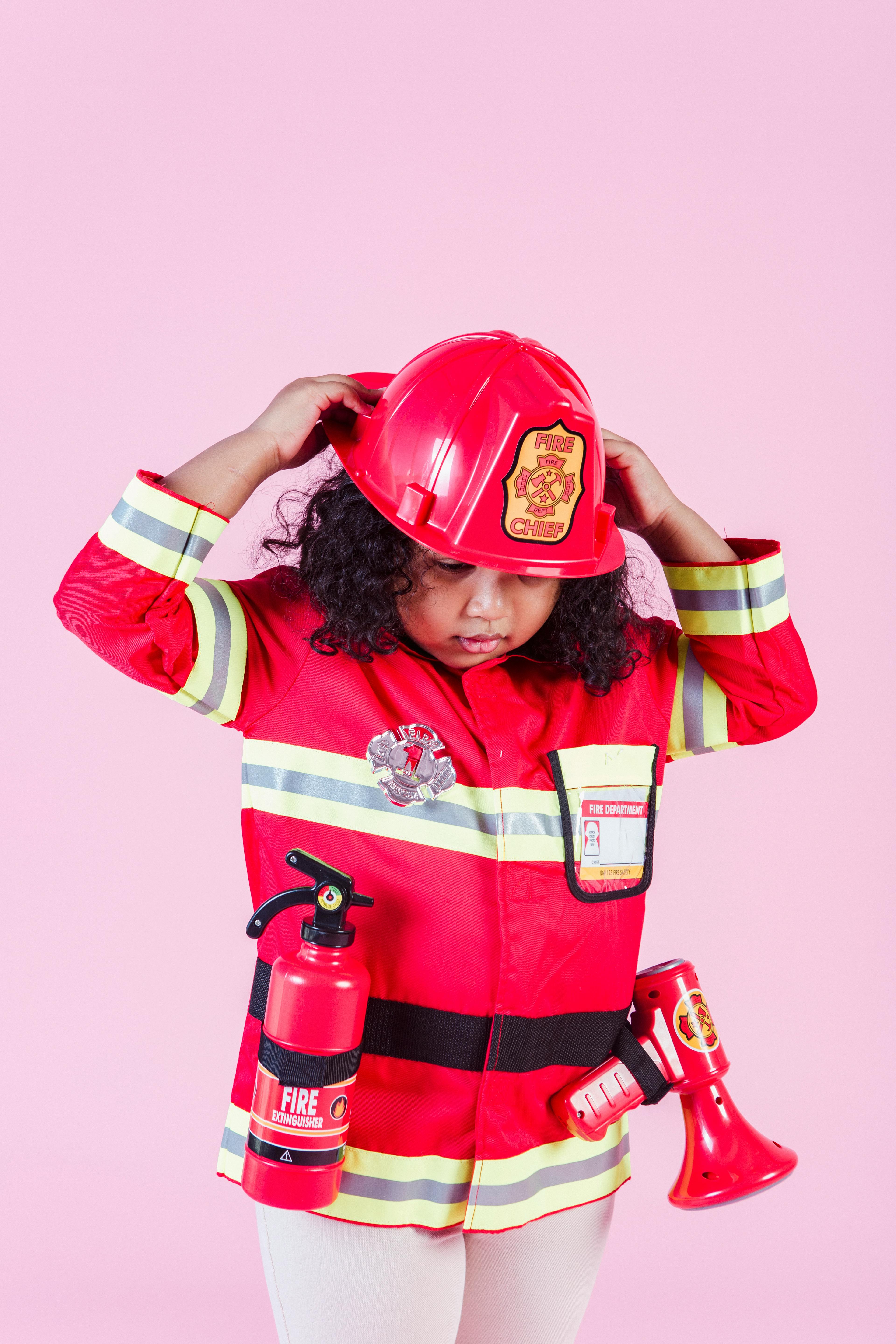 ethnic child wearing firefighter costume in room