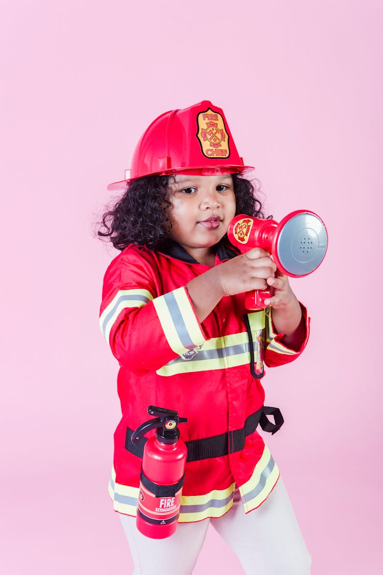 Little Ethnic Girl In Fireman Costume Using Loudspeaker