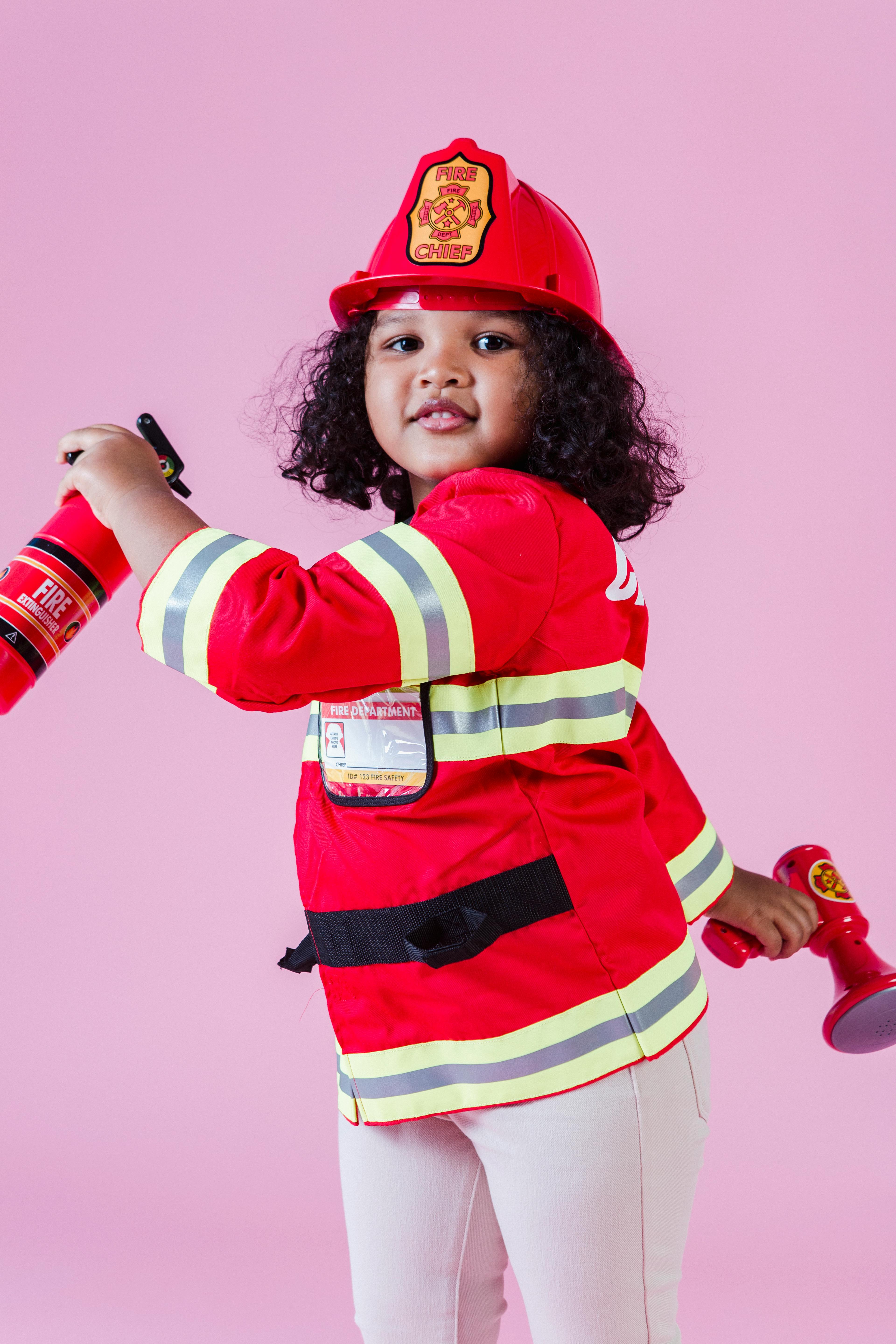 little ethnic girl wearing firefighter costume in studio