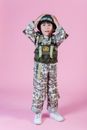 一个穿着海军海豹突击队服装的小男孩站在粉色背景前