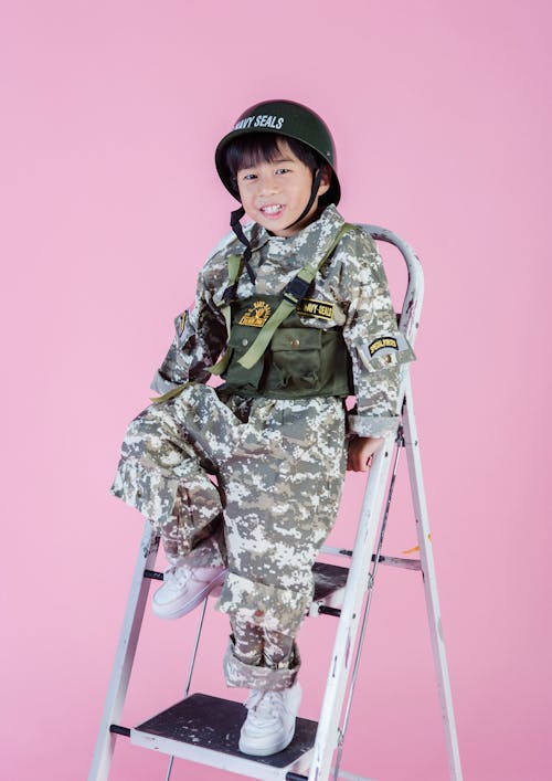 Smiling little Asian boy in navy uniform on ladder