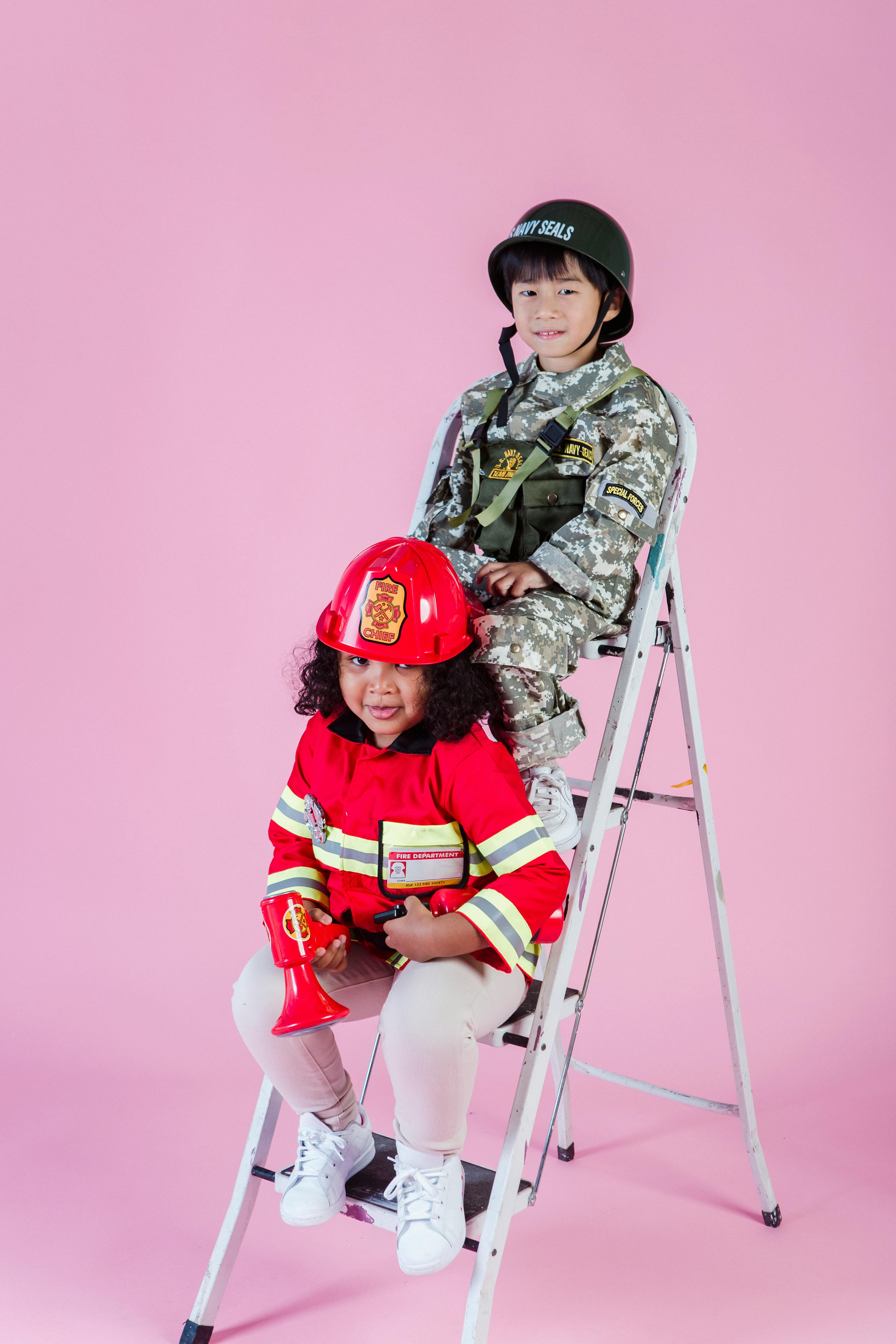 multiethnic kids wearing navy costume and firefighter costume in studio