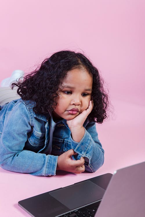 Little ethnic girl watching laptop in studio
