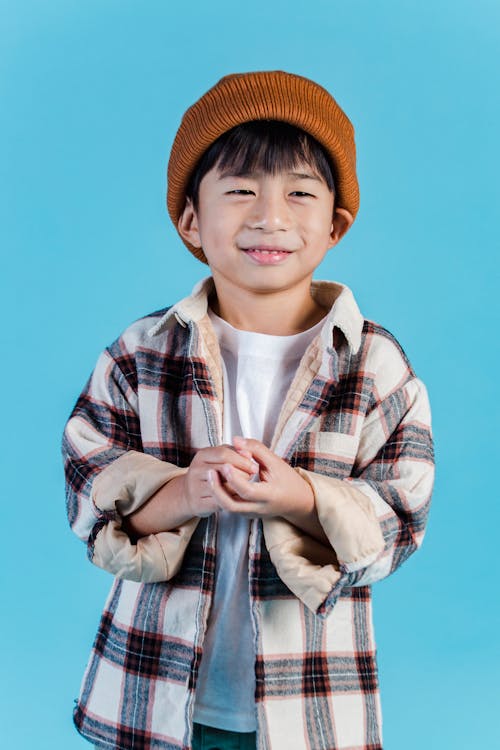 茶色のfedora帽子と格子縞のボタンアップシャツの少年