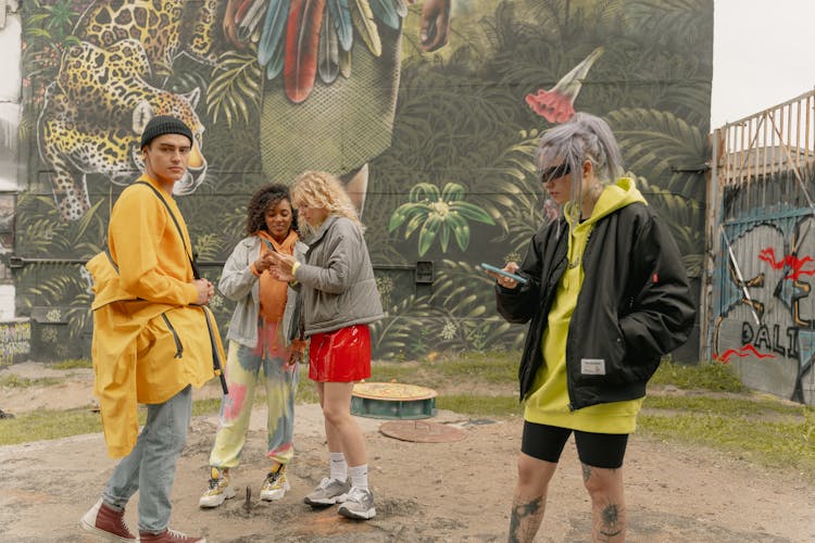 A Group Of People Standing Beside A Mural