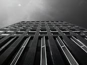 低角度视角下的现代建筑，窗户图案富有节奏，映衬着戏剧性的天空