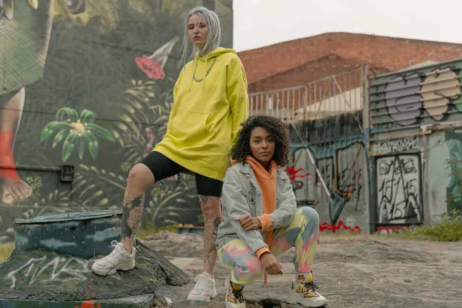 Deux femmes en hoodie jaune oversize posent devant un mur de graffitis
