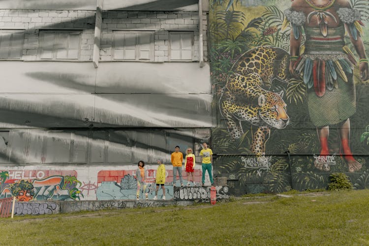 A Group Of People Standing Beside A Mural