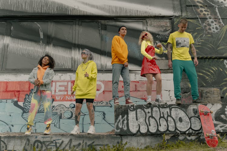 A Group Of People Dancing Beside A Wall With Graffiti