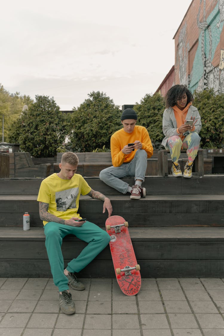 A Group Of People Sitting On Wooden Bleachers Holding Smartphones