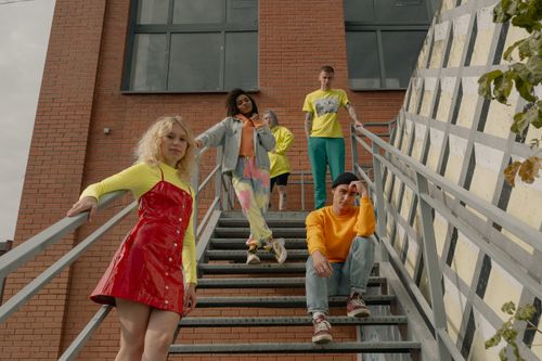 Free Diverse group posing stylishly on outdoor stairs by a brick building. Stock Photo
