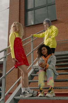 Three diverse women in grunge fashion posing on outdoor stairs.