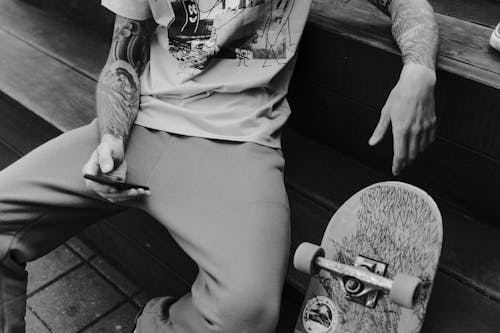 Grayscale Photo of Man in Shirt and Pants Sitting on Bench