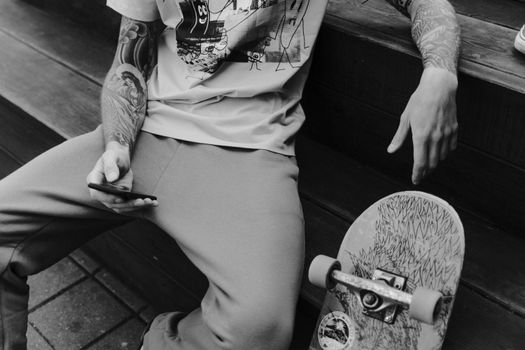 Grayscale Photo of Man Sitting on a Bench Holding a Smartphone