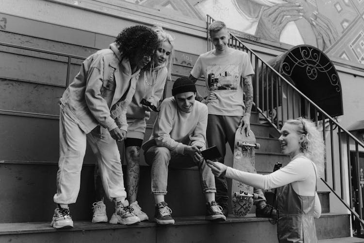 Grayscale Photo Of A Group Of People Looking At A Polaroid Picture