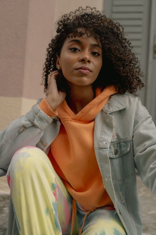 Free Portrait of a fashionable young woman in bright streetwear sitting outdoors. Stock Photo