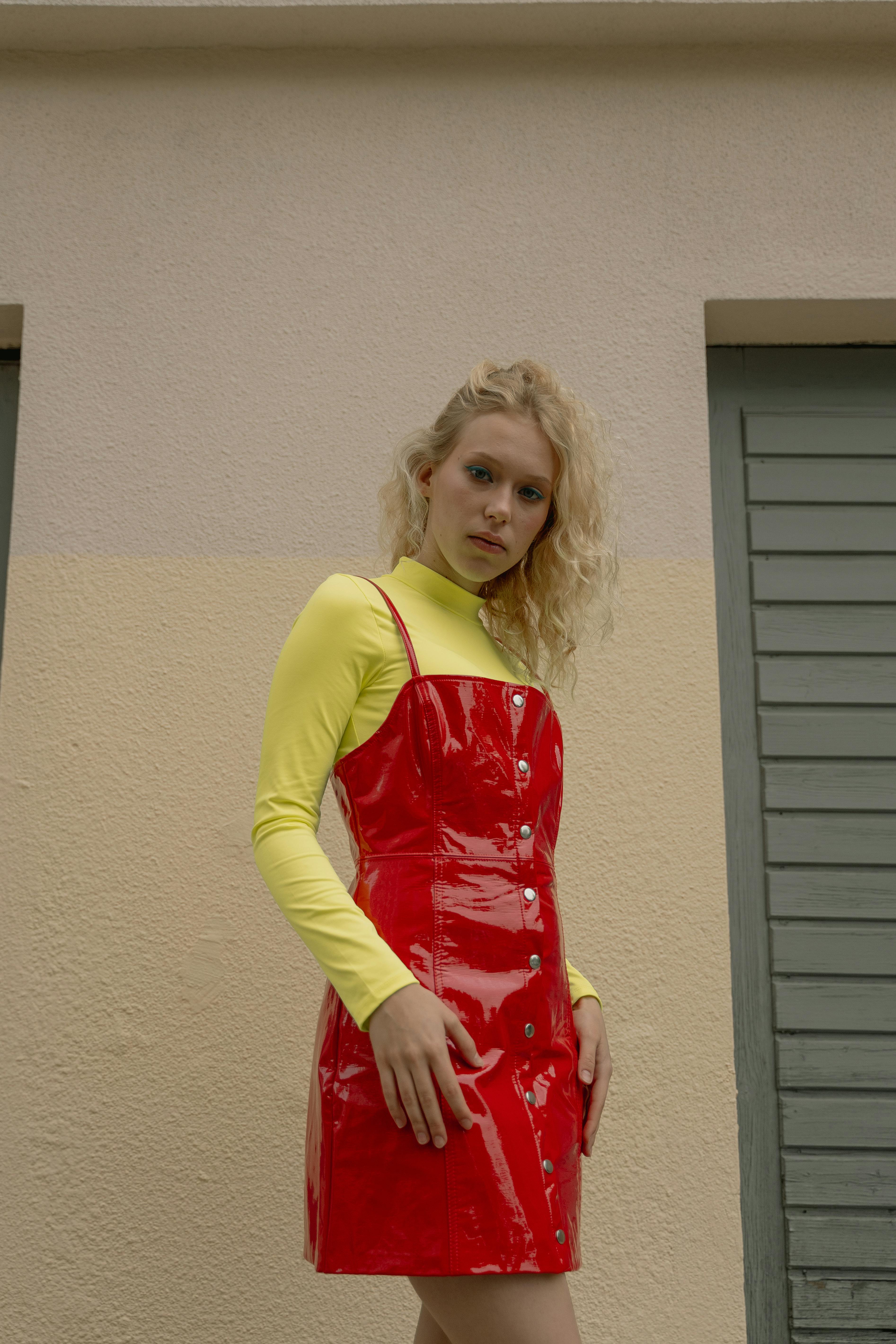 一位时尚女性在户外穿着红色漆皮连衣裙和黄色上衣