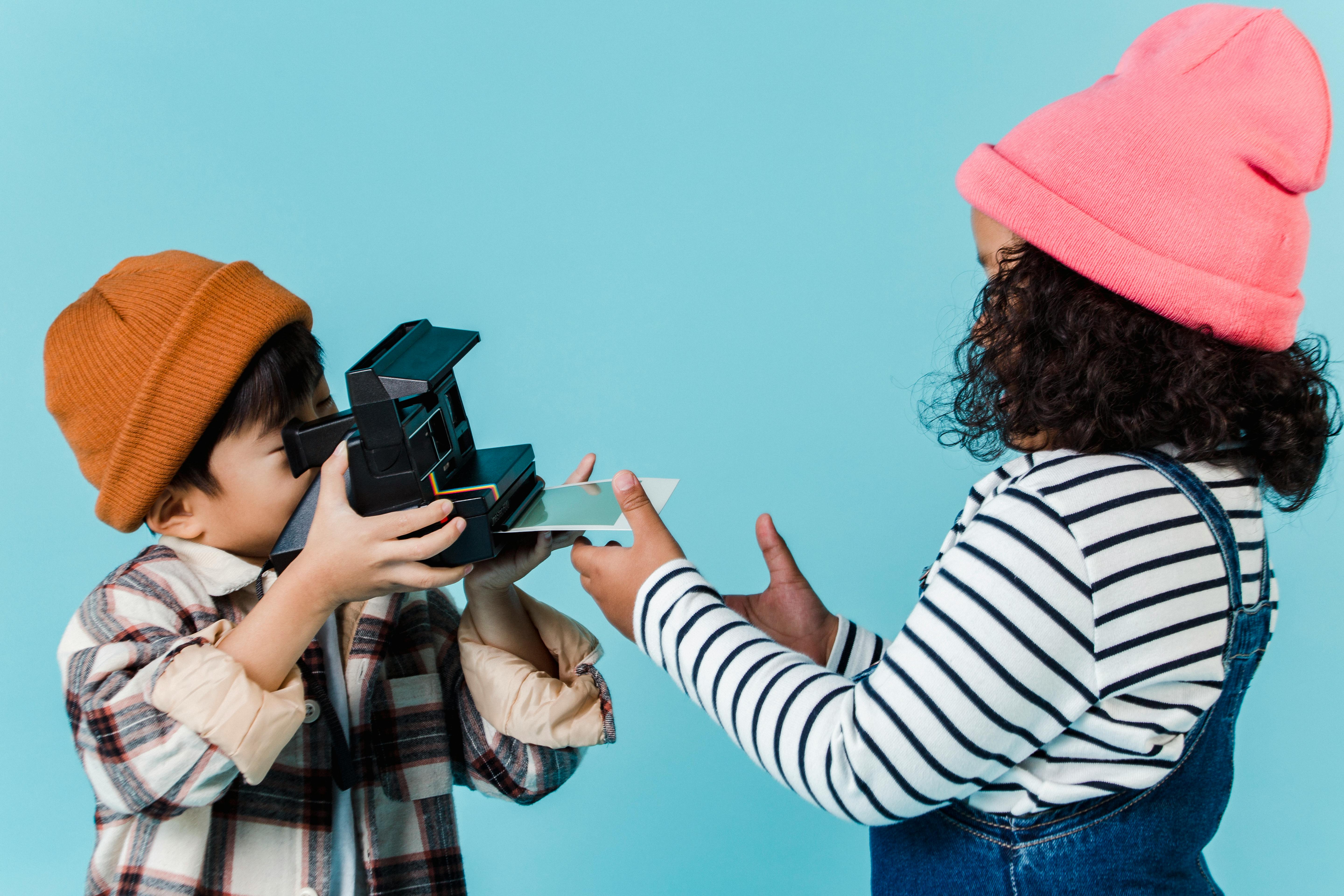 multiracial children taking photo on retro instant photo camera
