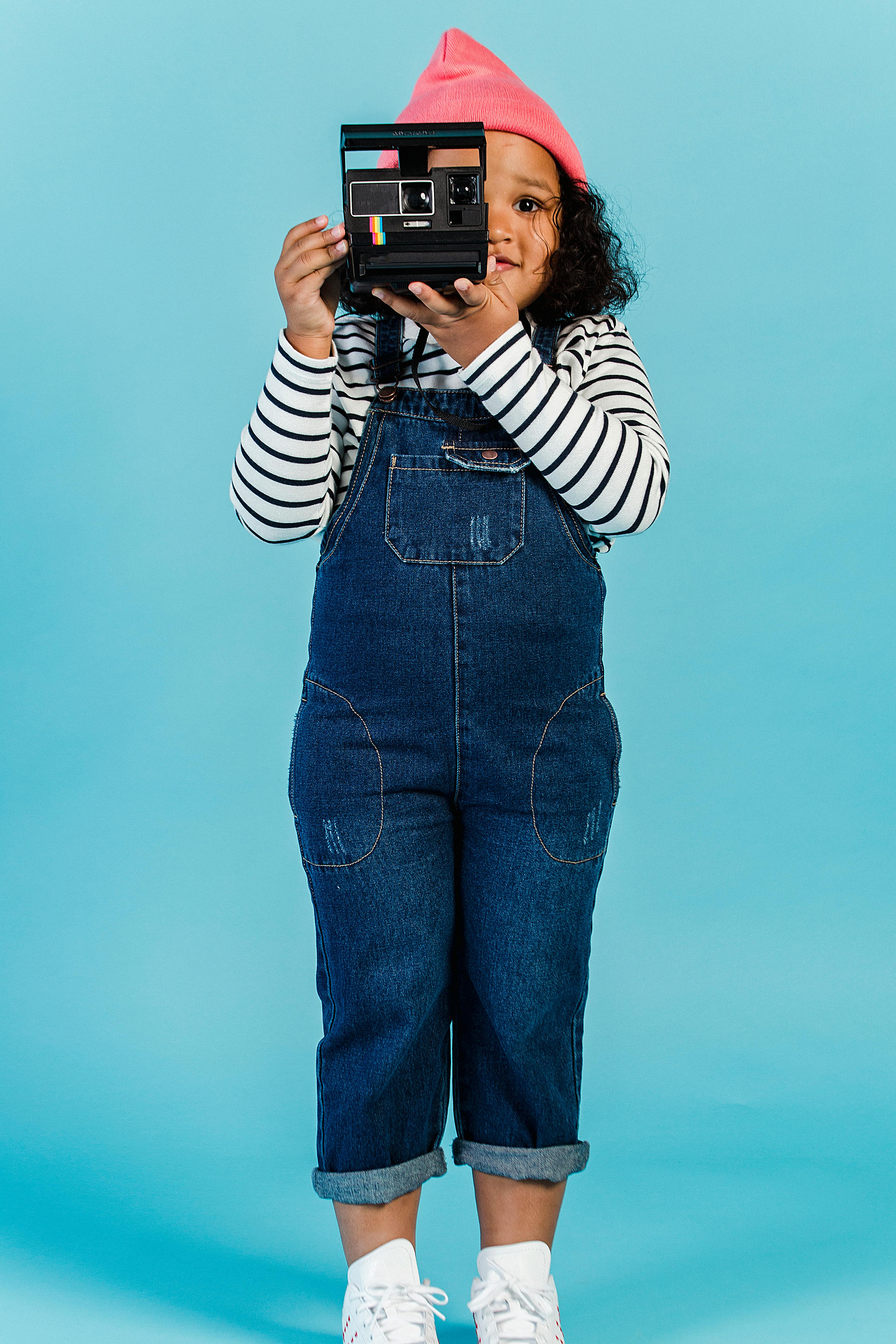 little african american girl taking instant photo in retro camera