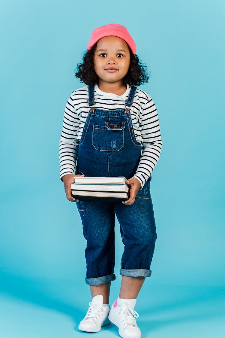 Cheerful Black Girl Standing With Books In Studio