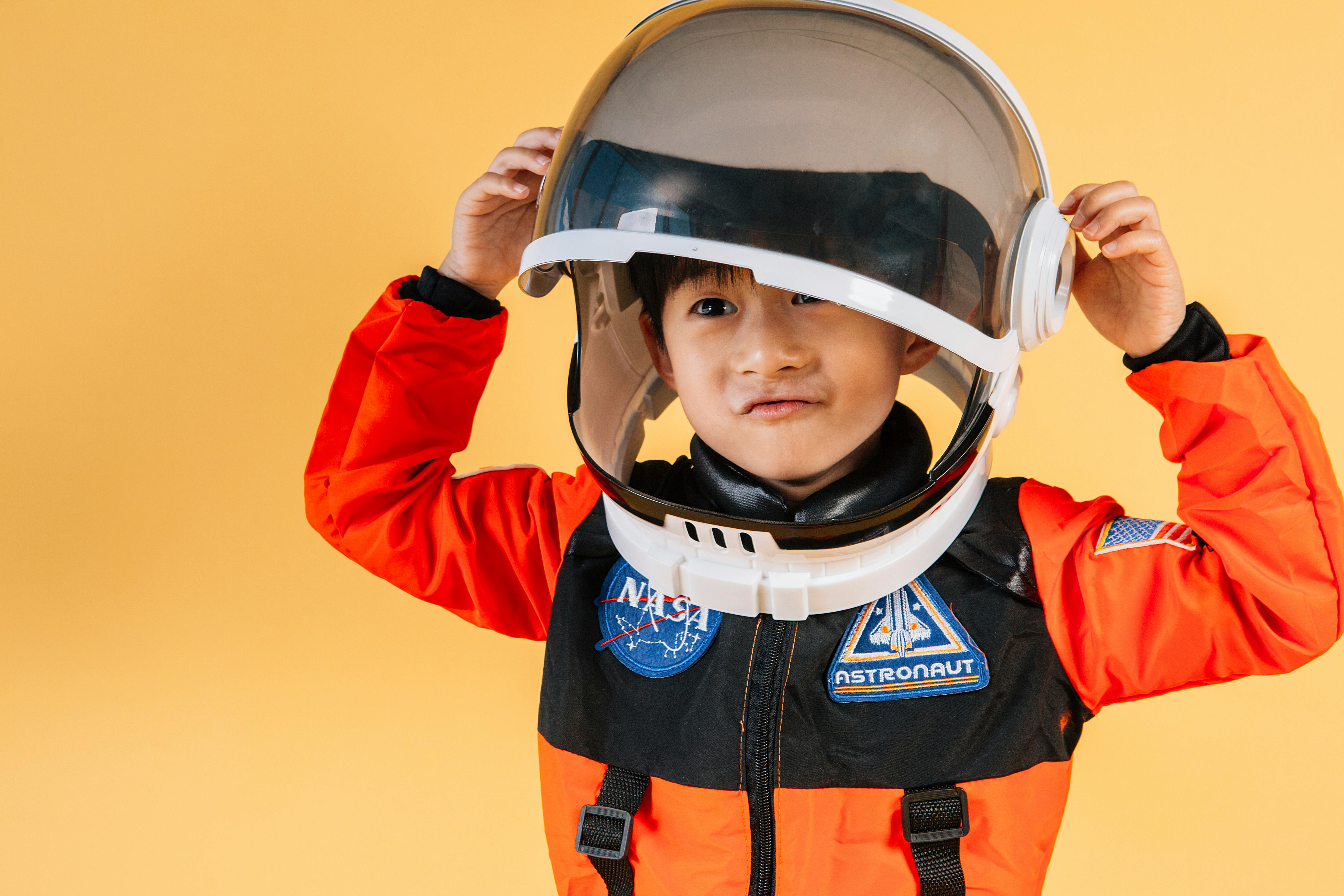 positive asian kid wearing cosmonaut helmet