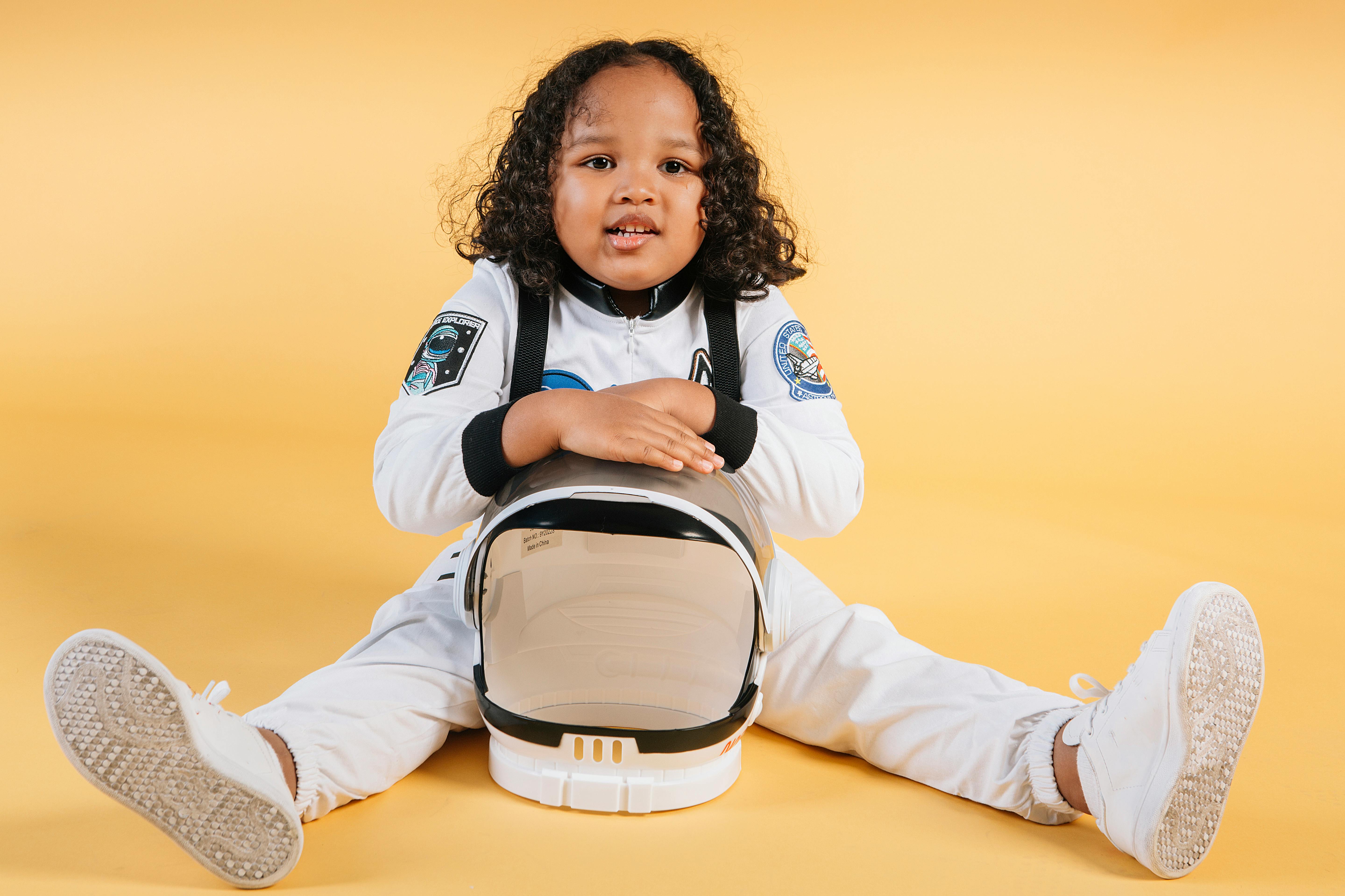 little ethnic girl sitting with space helmet