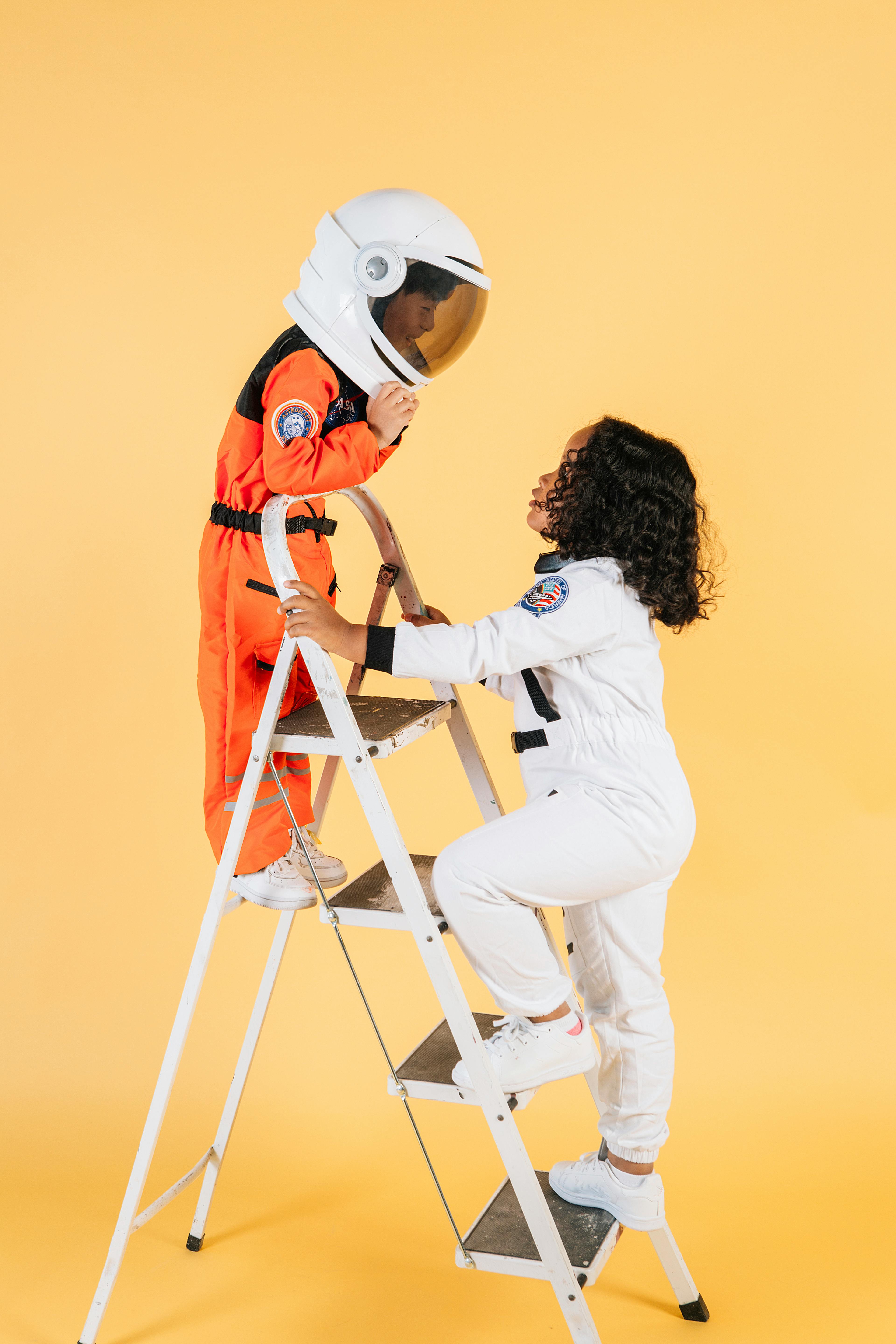 children in astronaut costumes playing in studio with yellow walls