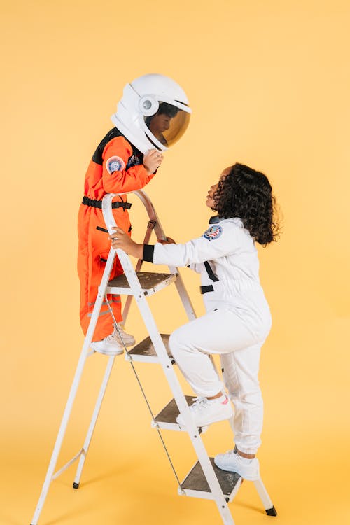 Children in astronaut costumes playing in studio with yellow walls