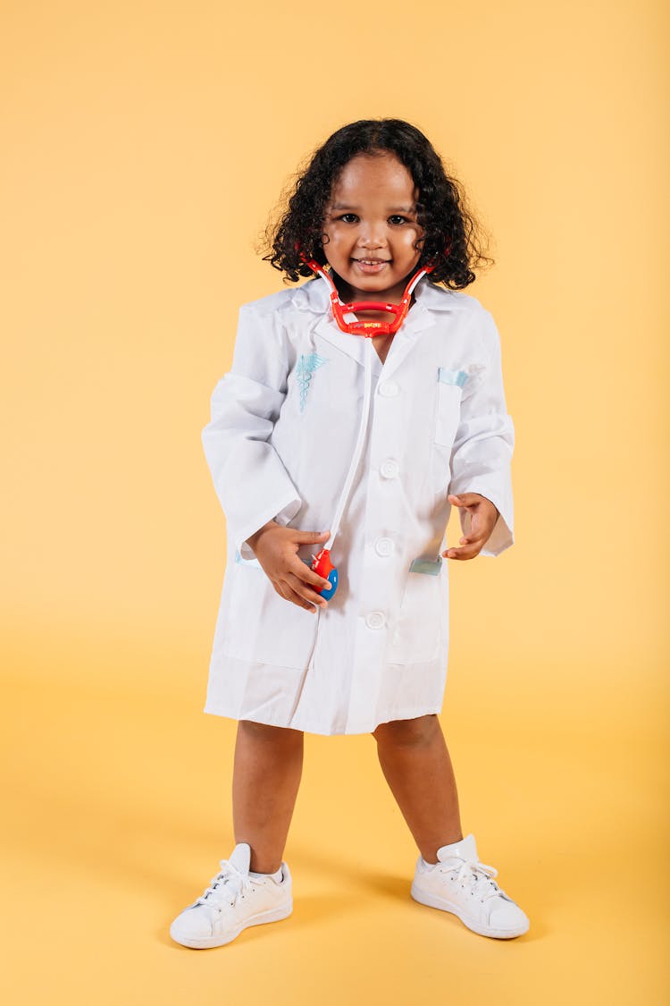 Smiling Black Girl In Medical Costume Standing In Studio With Yellow Background