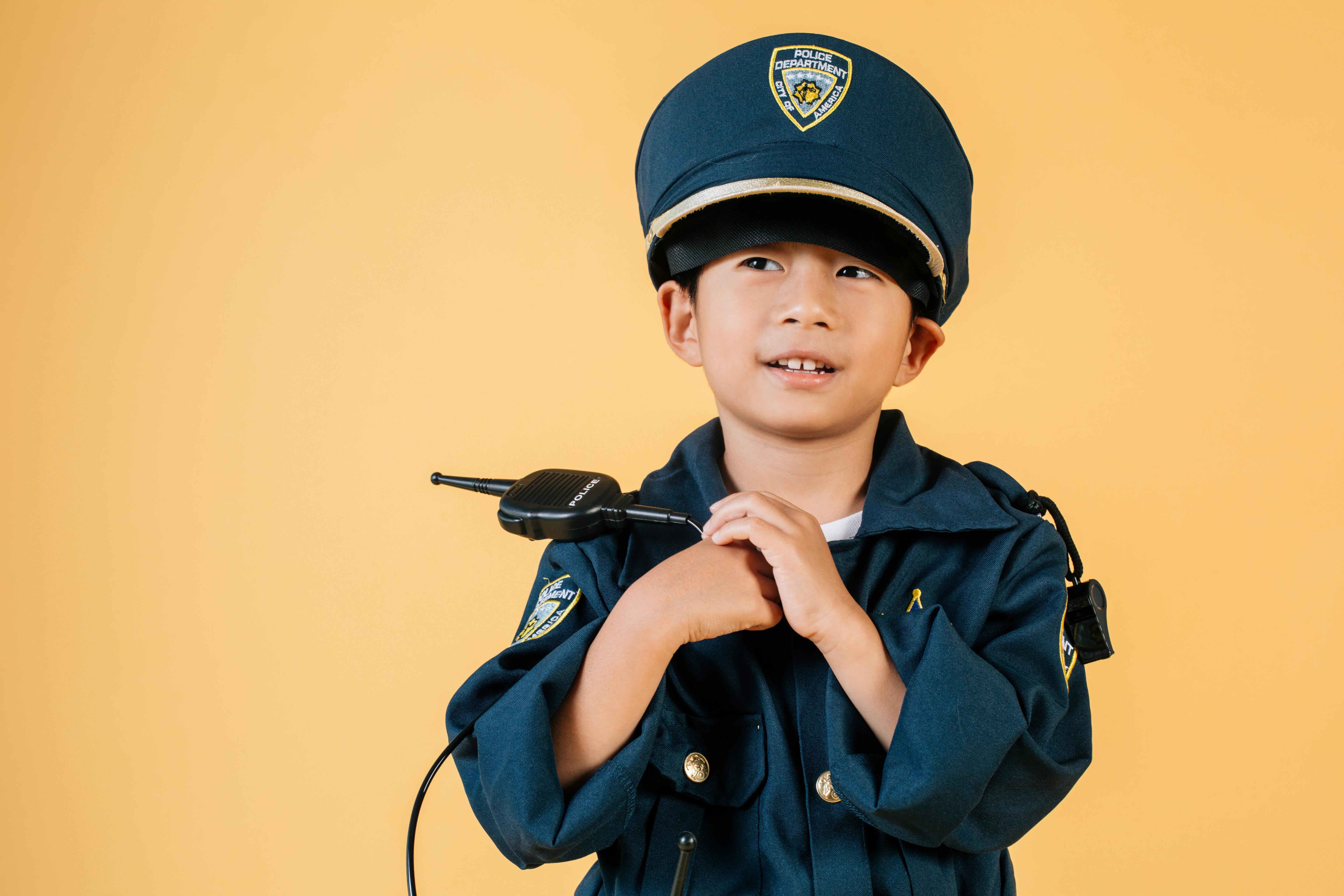 pleasant ethic boy in police uniform in photo studio