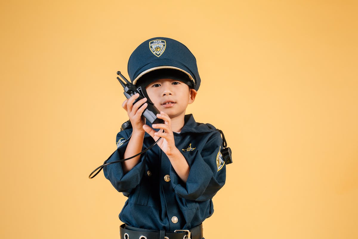 Serious Asian kid in police uniform with transceiver