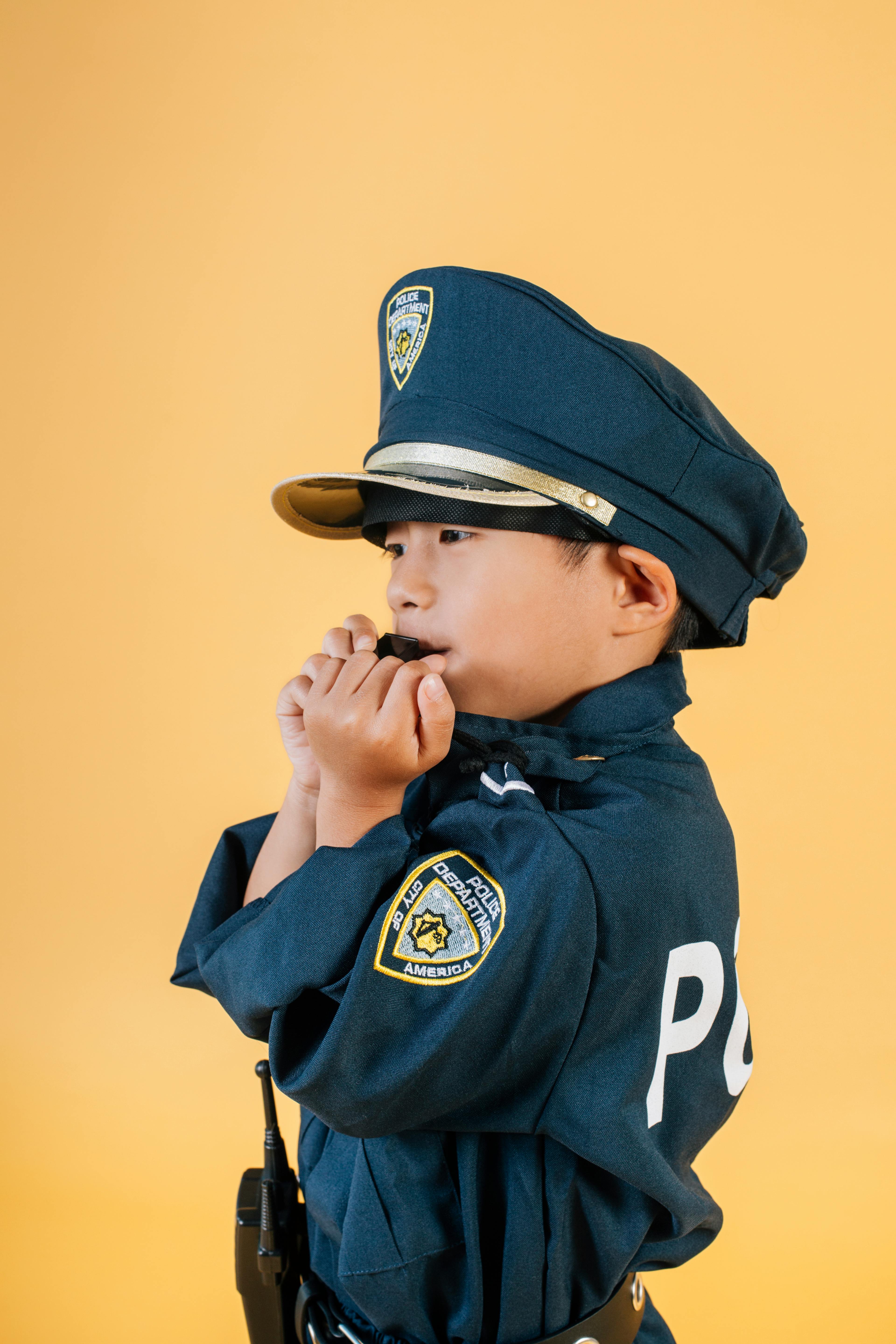 asian kid in police uniform blowing whistle in studio