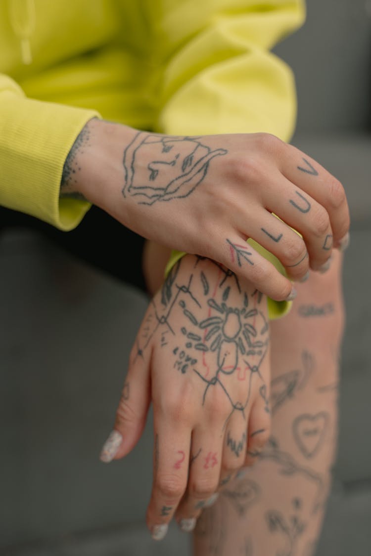 A Person In Yellow Long Sleeve Shirt With Tattoo On Both Hands