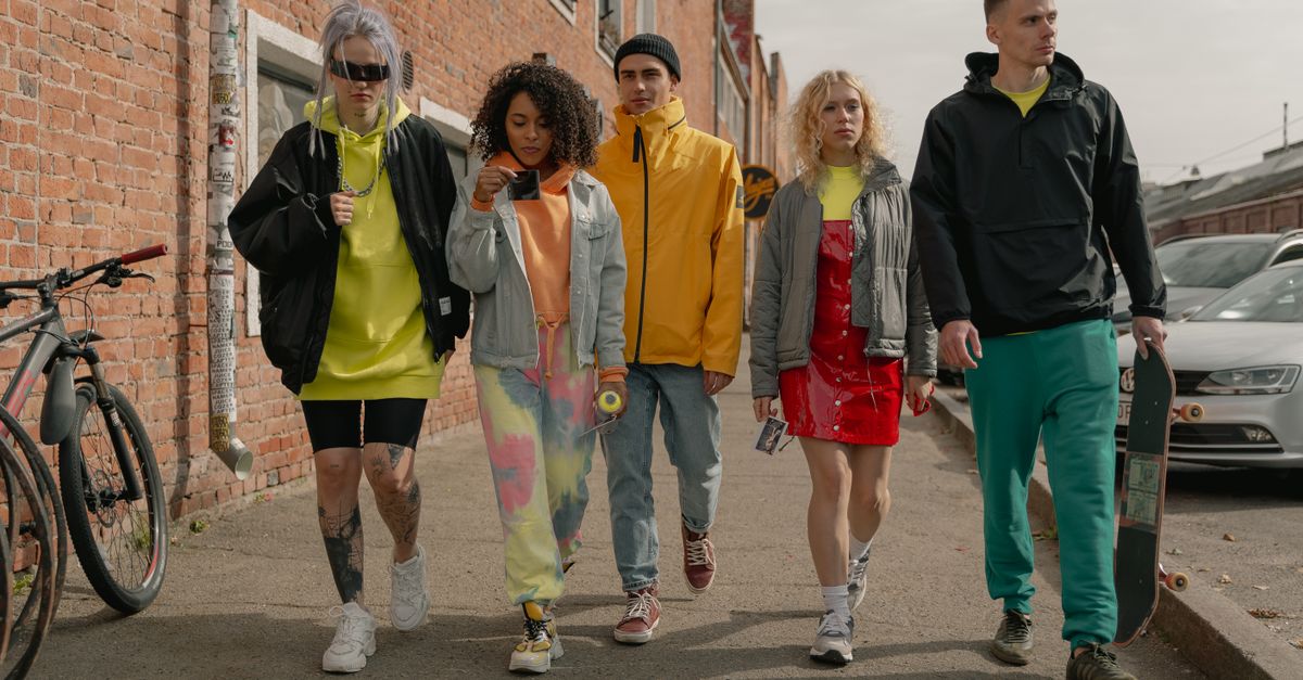 A group of young, diverse people in expensive streetwear laughing in front of a private jet
