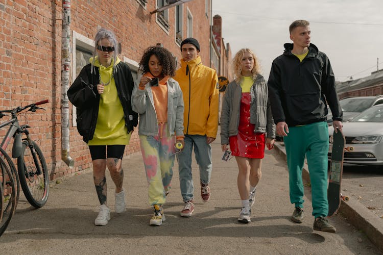 A Group Of People Wearing Jackets Walking Together On Pavement