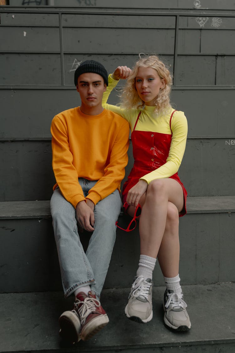 A Man And A Woman Sitting Close Together On Gray Bench