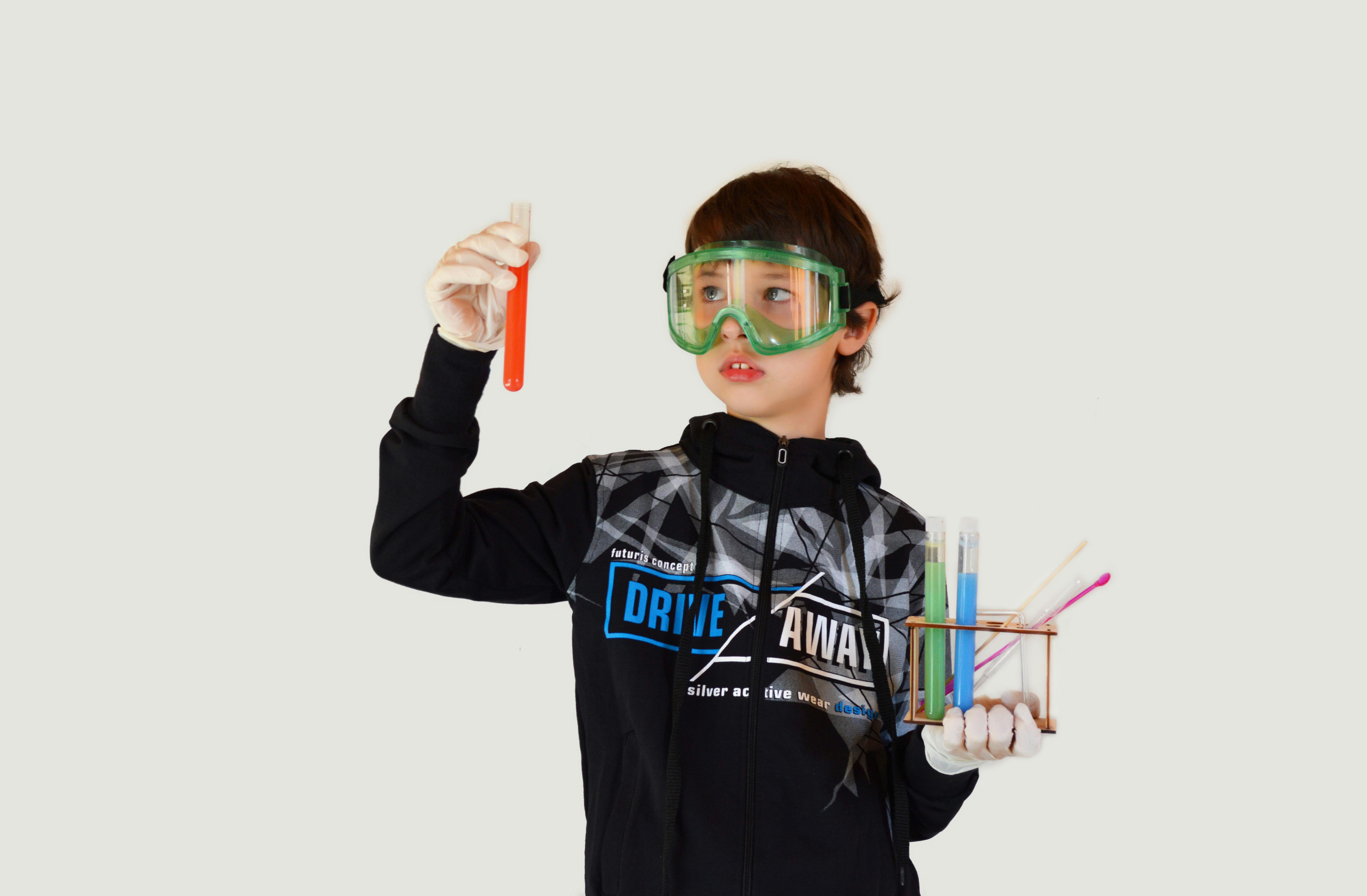 boy with assorted test tubes on light background