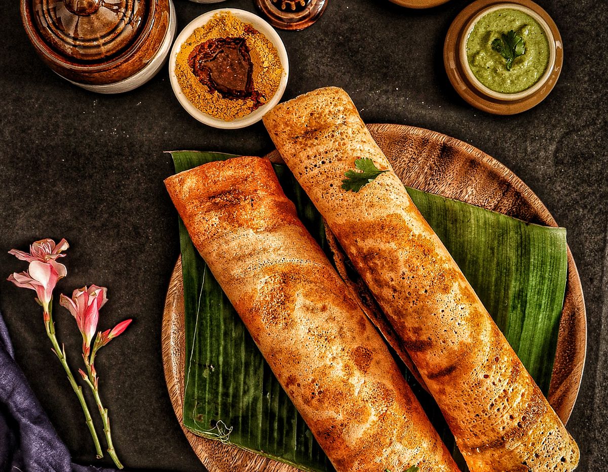 Dosa with chutneys and sambar on banana leaves