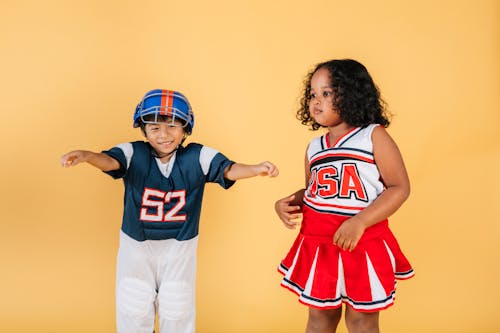 Cheerful multiracial kids wearing football player and cheerleader costumes