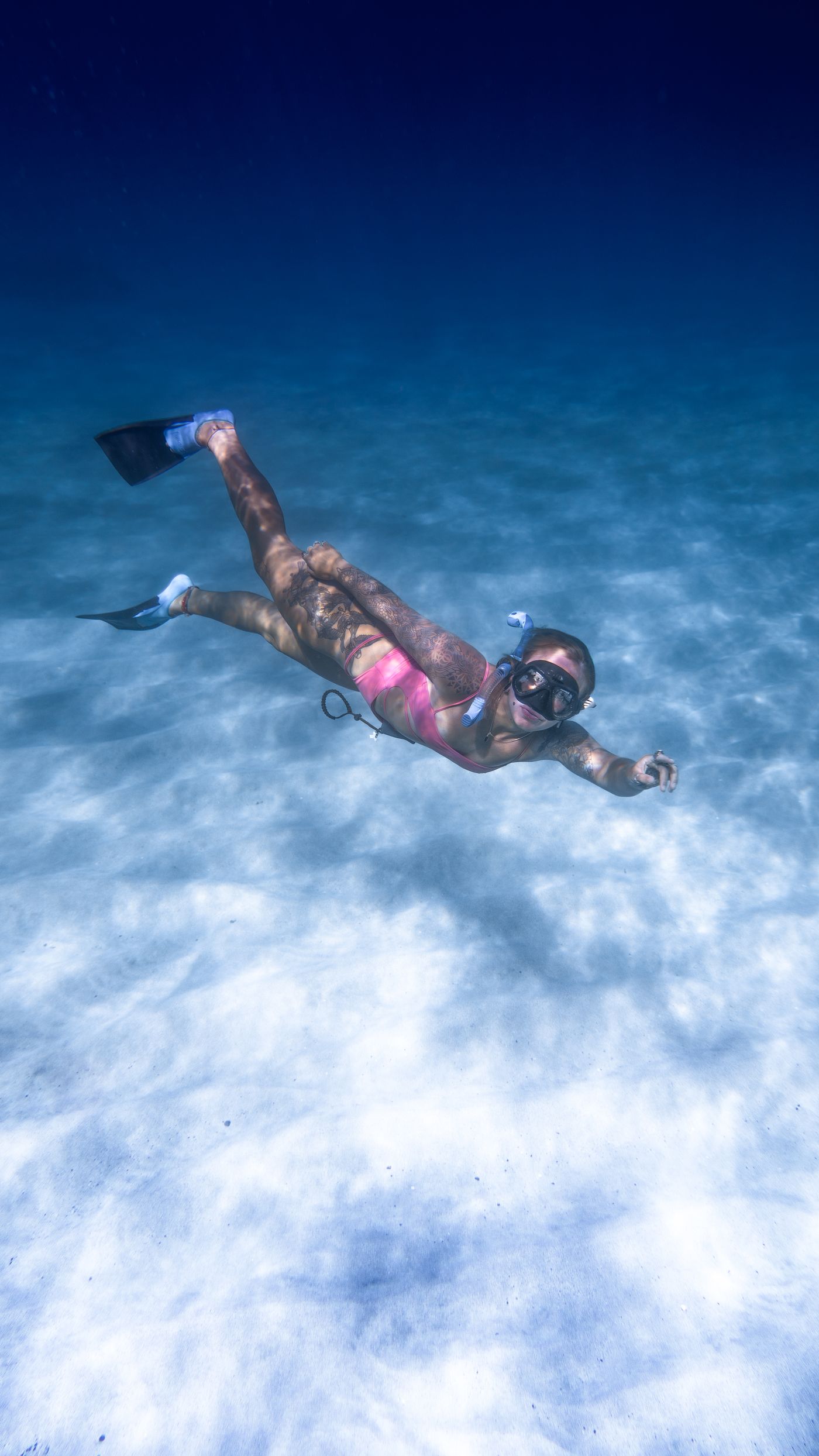Woman wearing fins and a snorkeling mask while swimming underwater