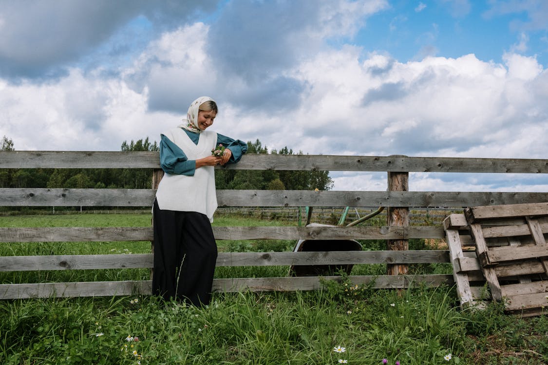 A Woman with Headscarf Leaning on a Wooden Fence